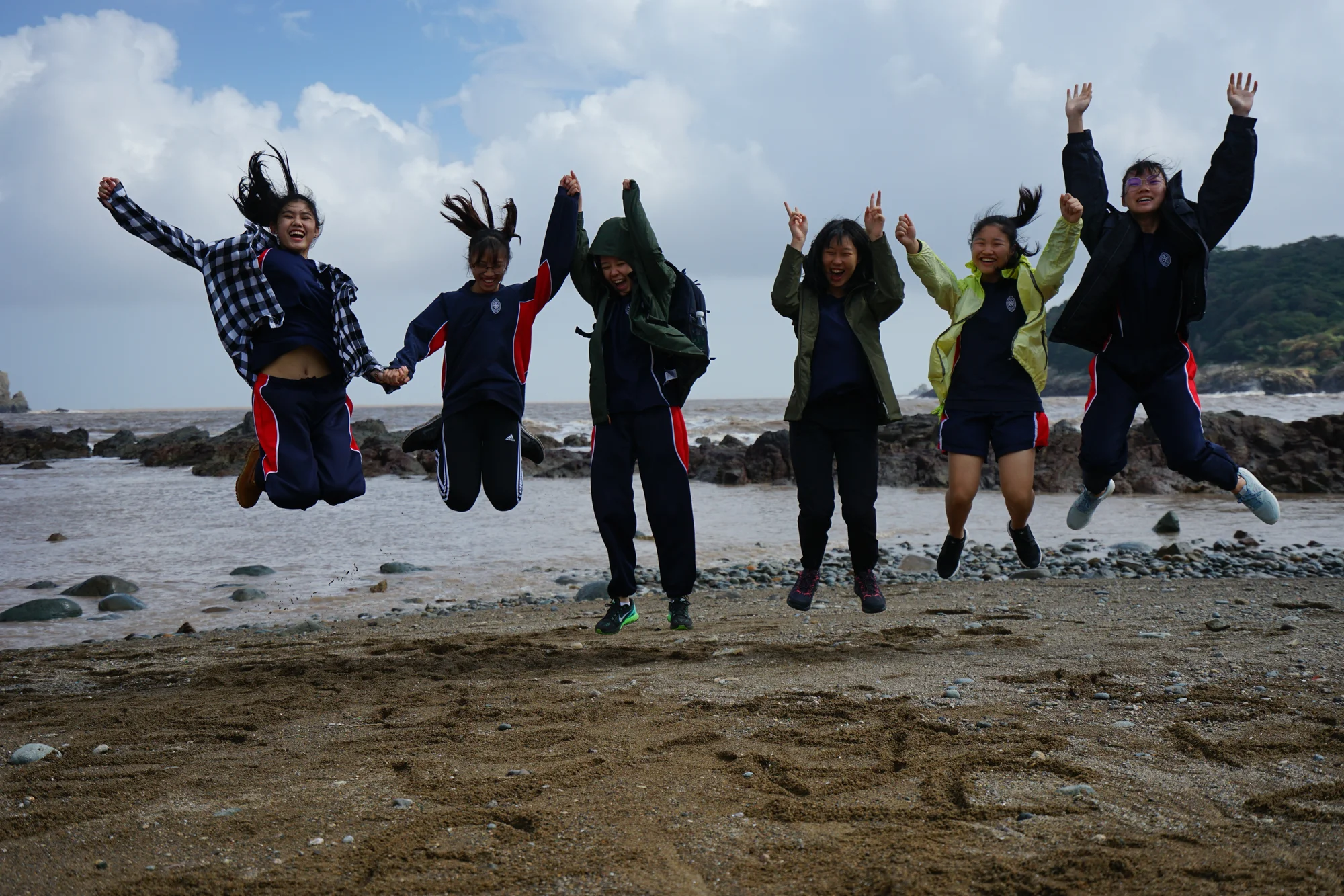 Students jumping in the air at the end of their coastal studies