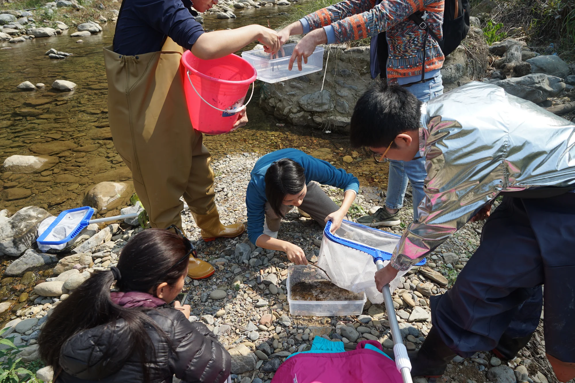 3 students working on kick sampeling data collection from the river